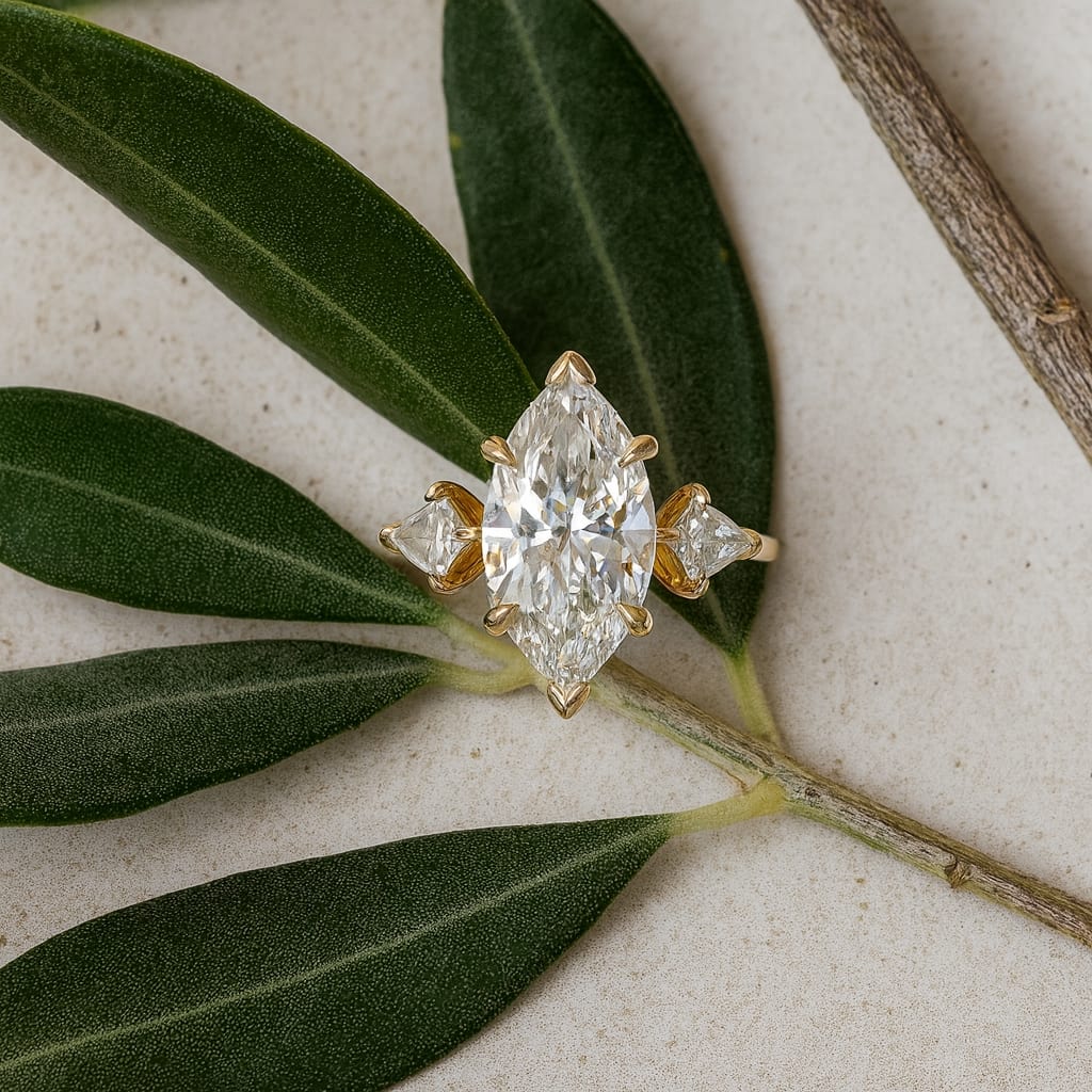 Marquise diamond three-stone in yellow gold with kite-cut side stones, styled on olive branch