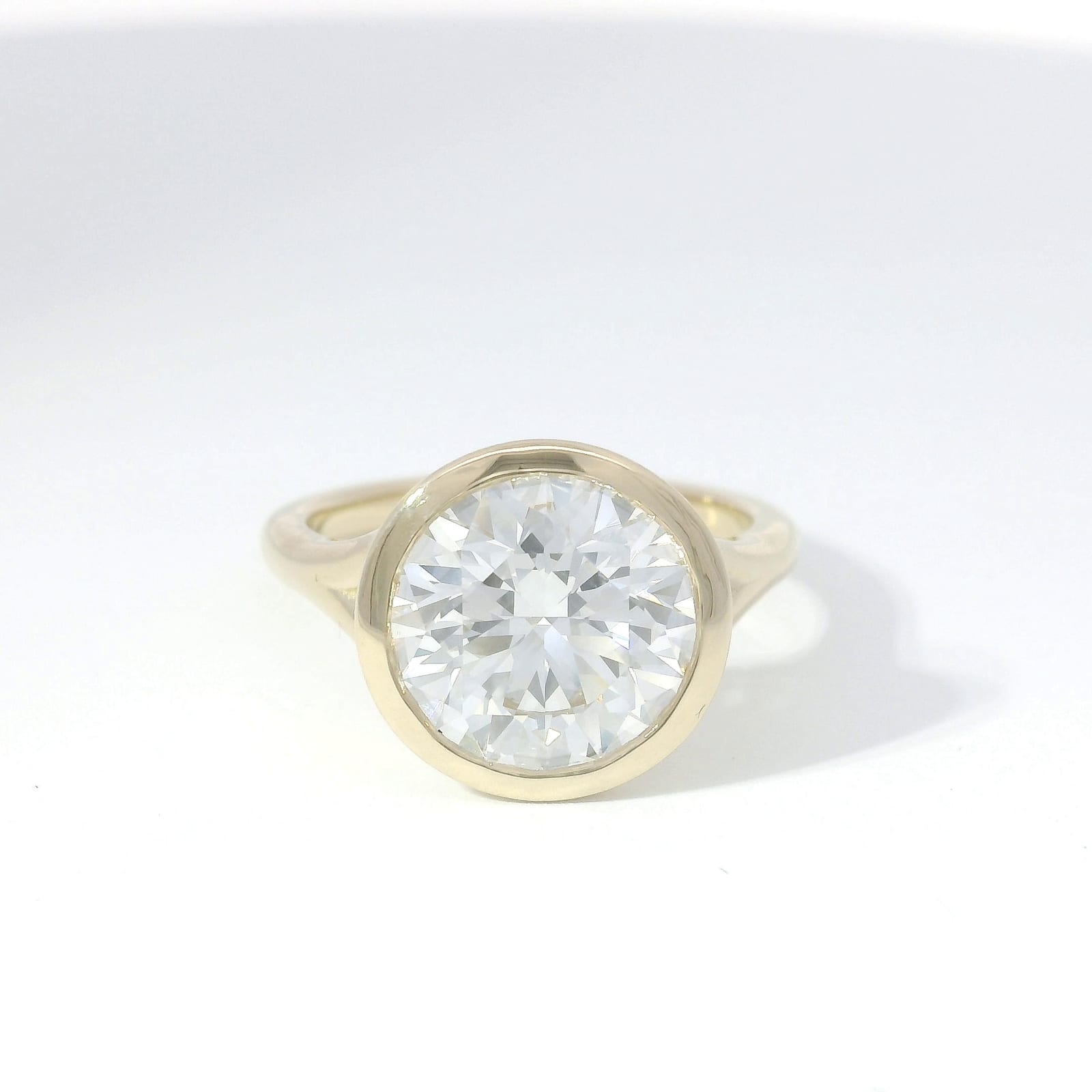 Bezel-set round brilliant diamond solitaire in yellow gold