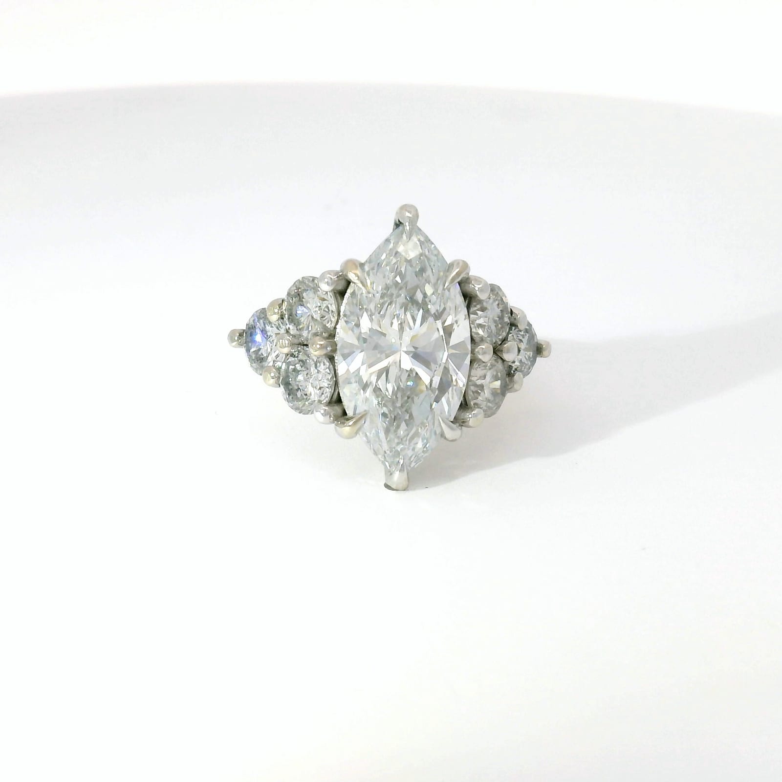 Marquise-cut diamond with round diamond cluster side stones in platinum