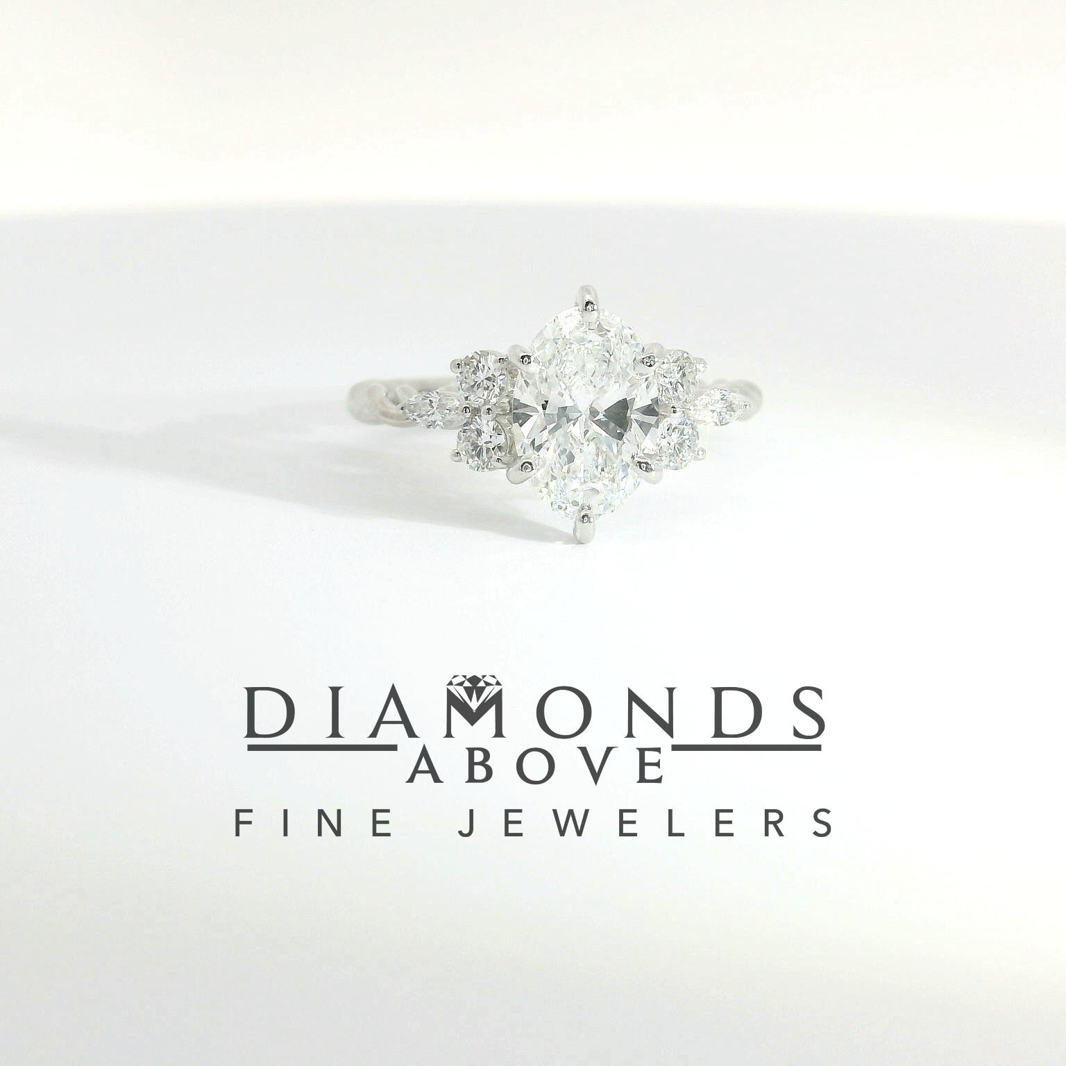 Oval diamond with pear-shape and round diamond side clusters in white gold