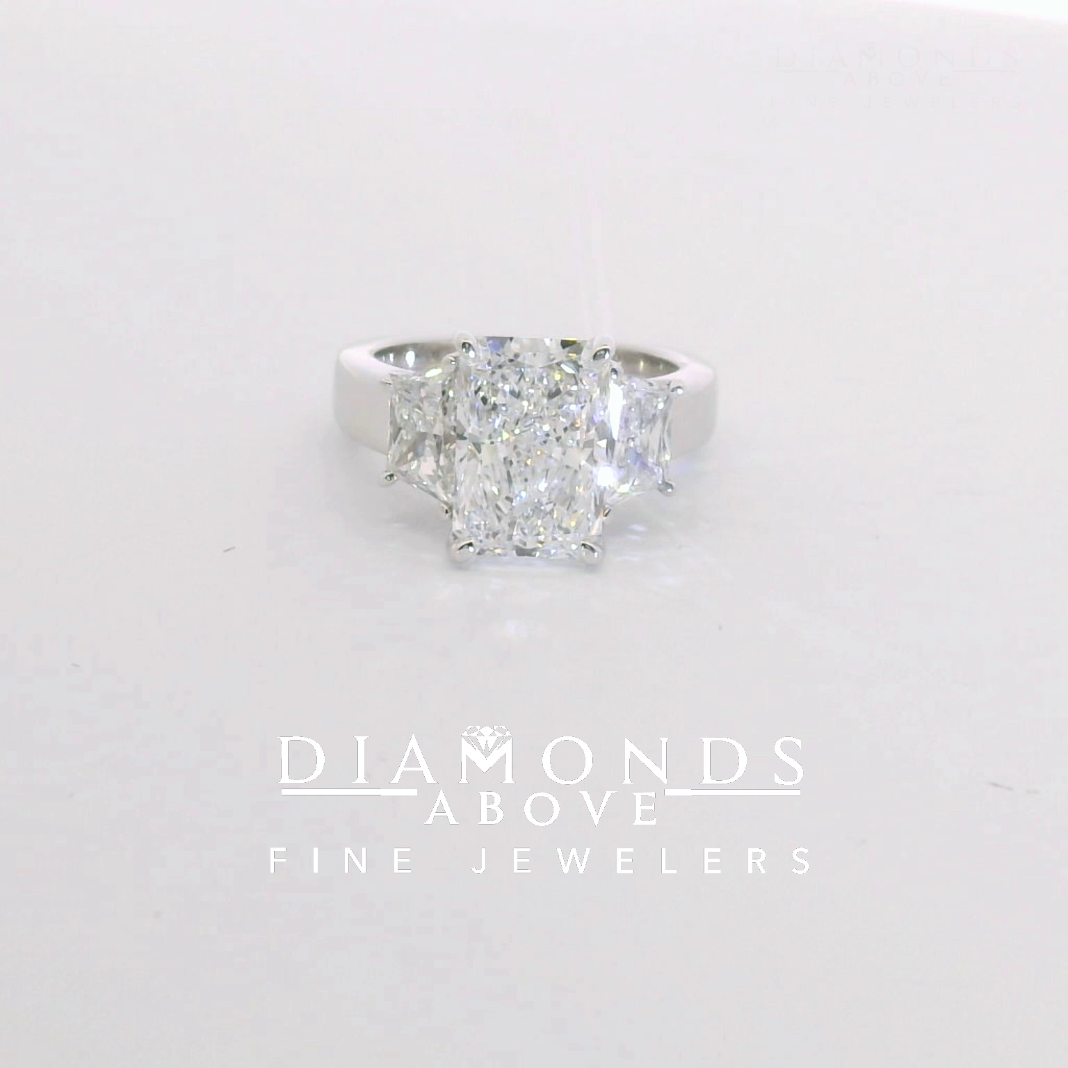 Radiant-cut diamond three-stone with trapezoid side stones in white gold