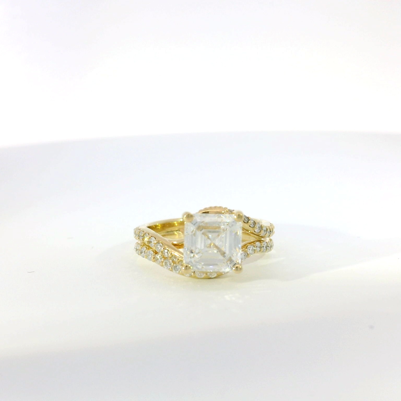 Emerald-cut diamond with split-shank pavé band in yellow gold