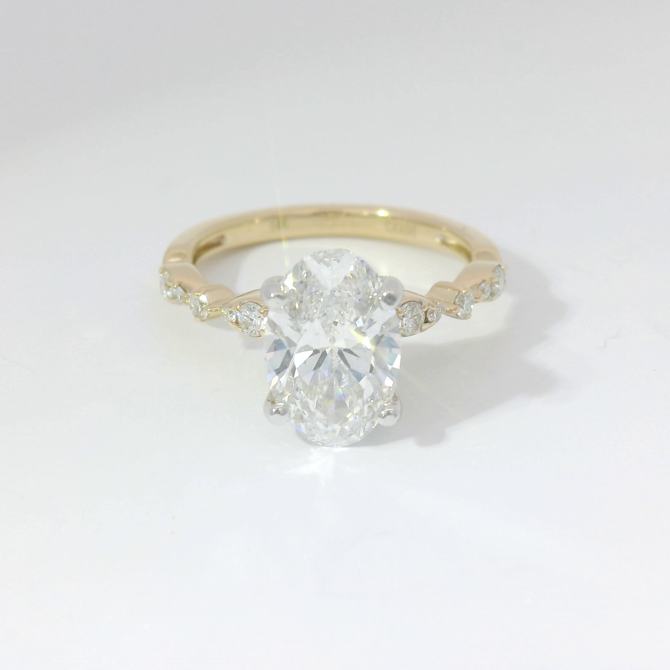 Oval diamond solitaire on a yellow-gold band with diamond floral accents