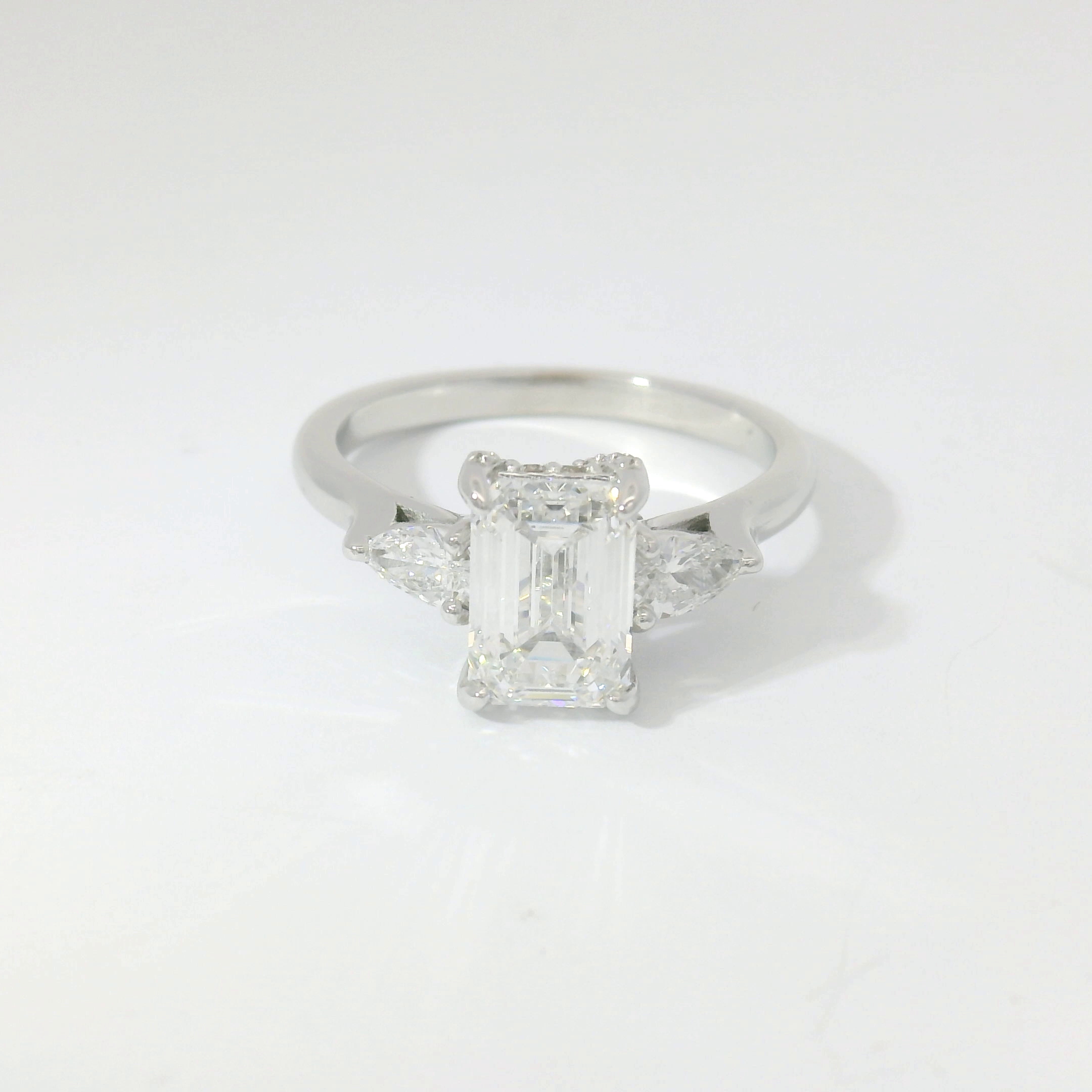 Emerald-cut diamond three-stone with pear-shape side stones in platinum