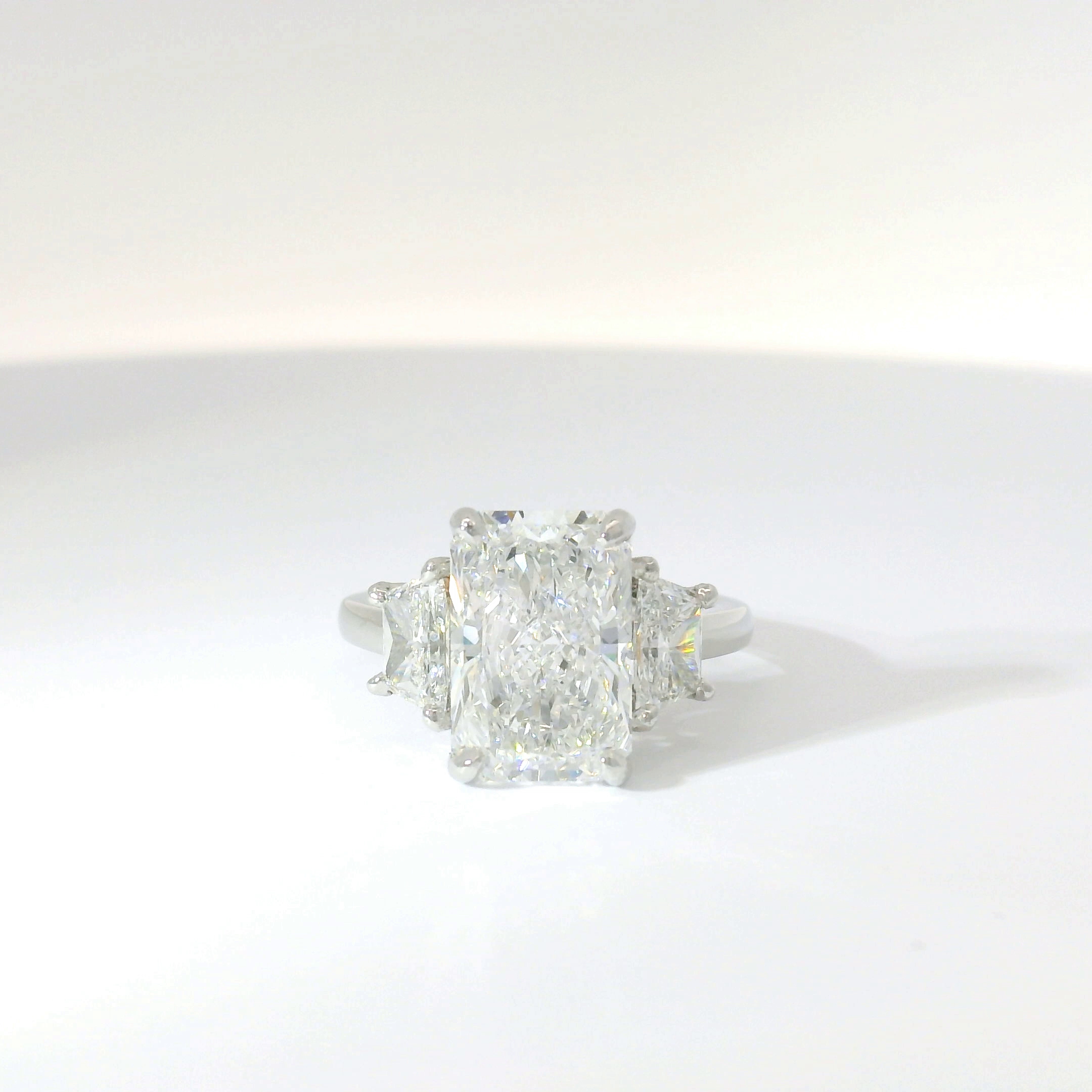 Radiant-cut diamond three-stone with trapezoid side stones in platinum