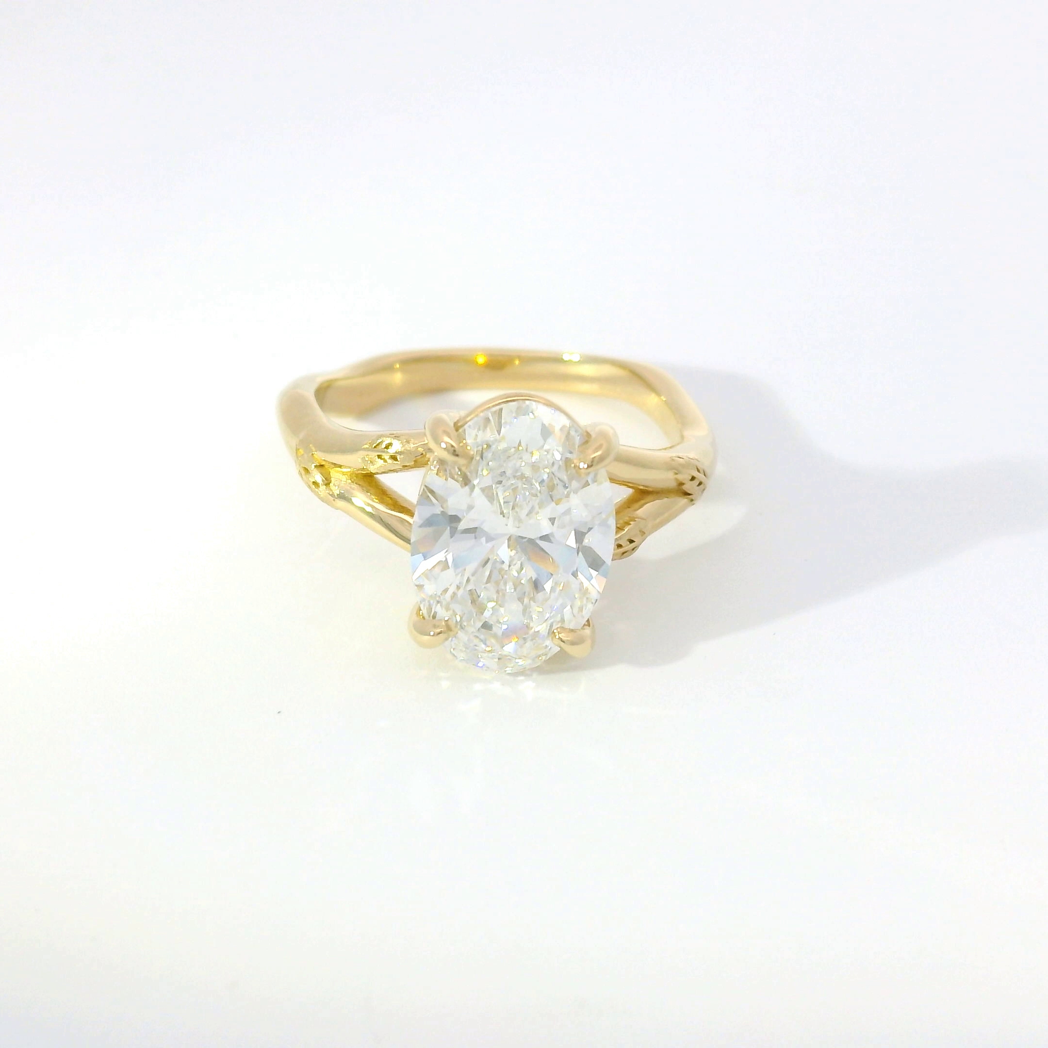 Oval diamond solitaire set on an organic, textured yellow gold band
