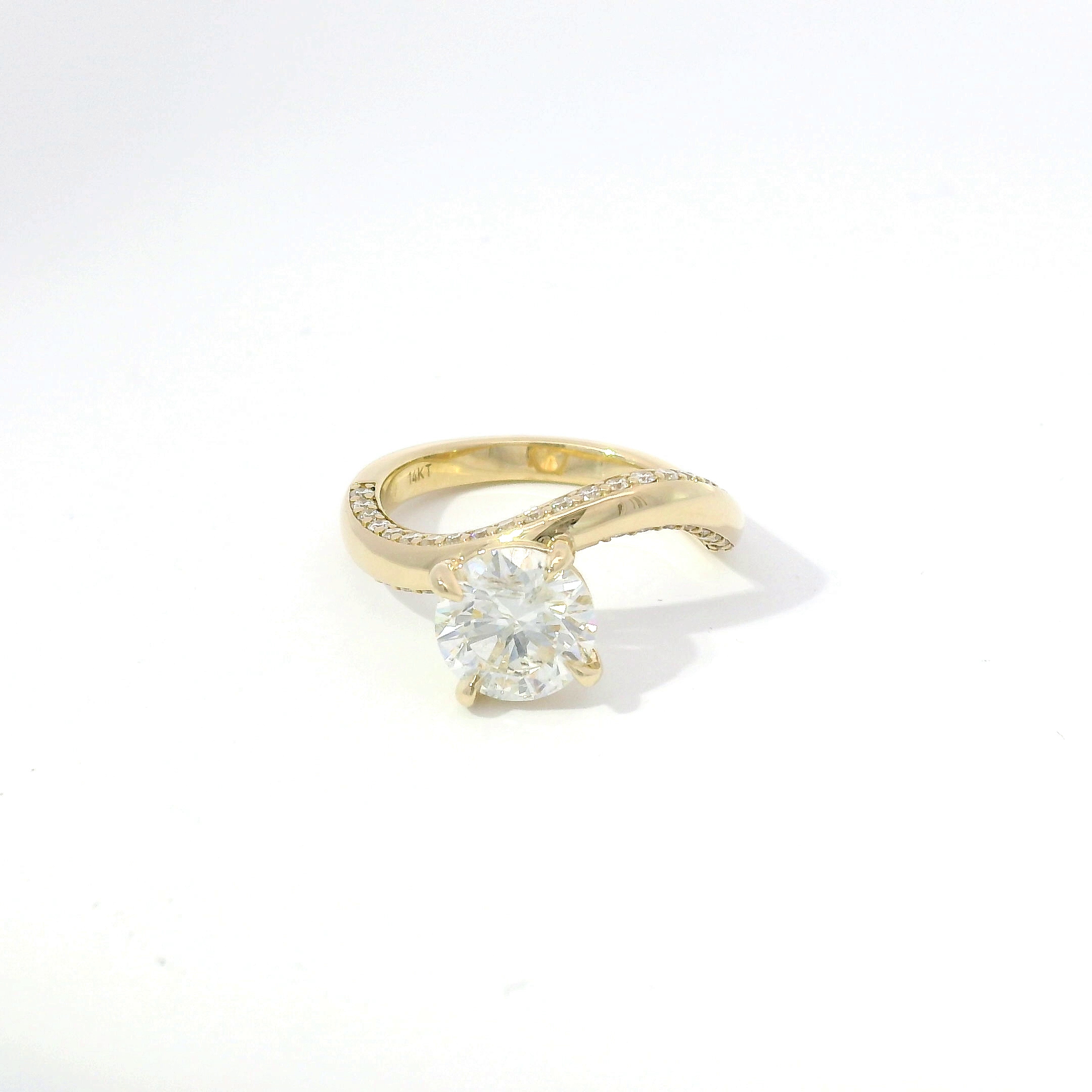 Round brilliant diamond with diamond pavé bypass shank in yellow gold