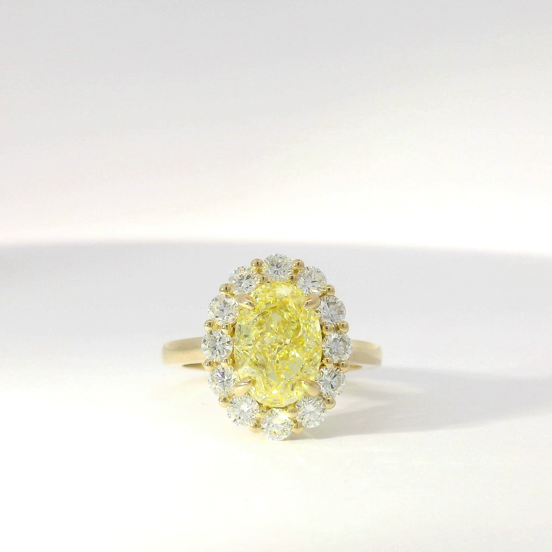 Fancy yellow oval diamond with diamond halo in yellow gold