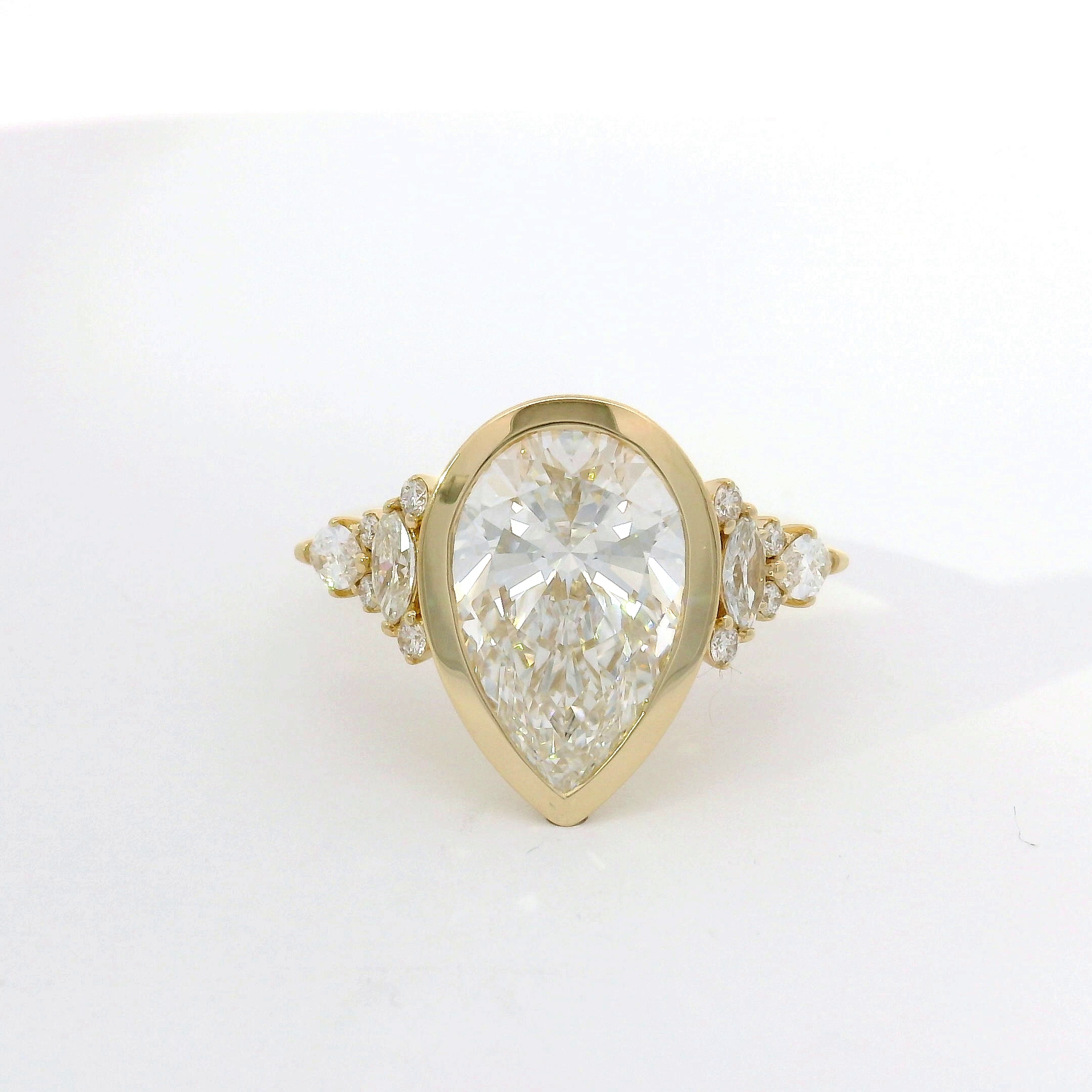 Pear-shape diamond in yellow-gold bezel with marquise and round diamond side accents