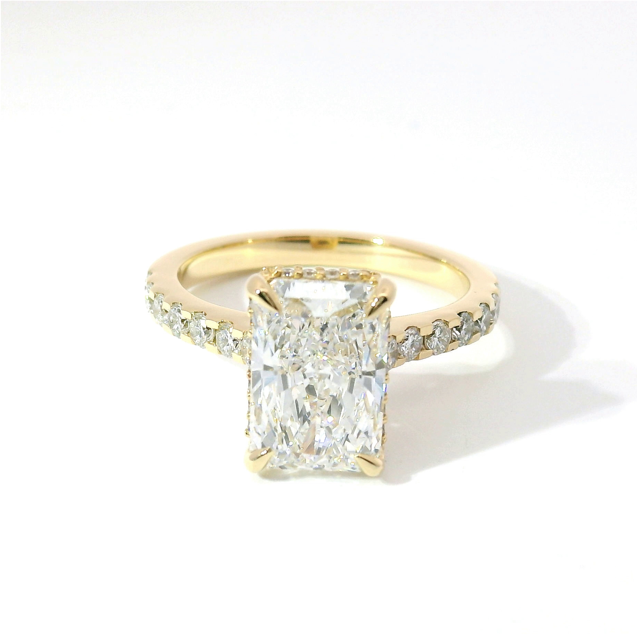 Radiant-cut diamond solitaire with pavé band in yellow gold