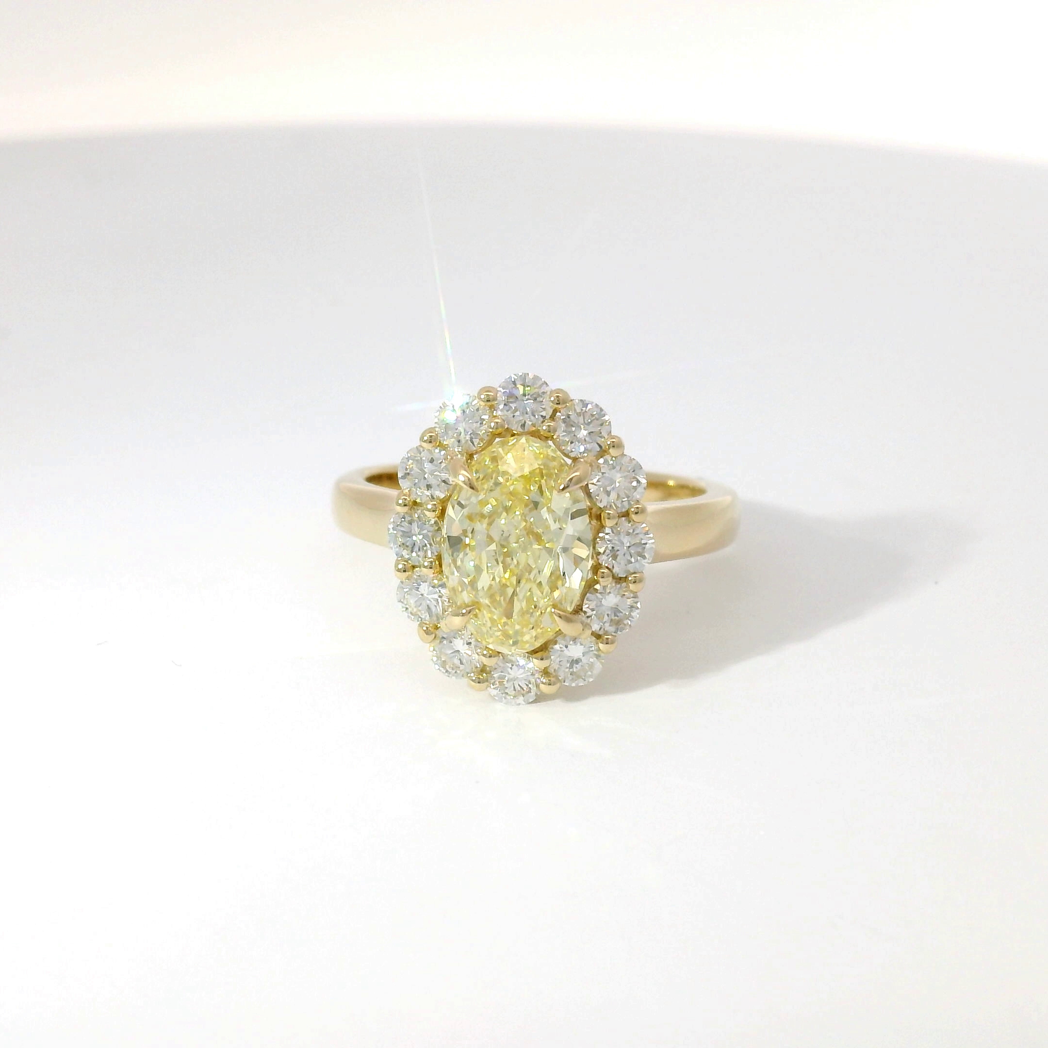 Fancy yellow oval diamond with diamond halo in yellow gold