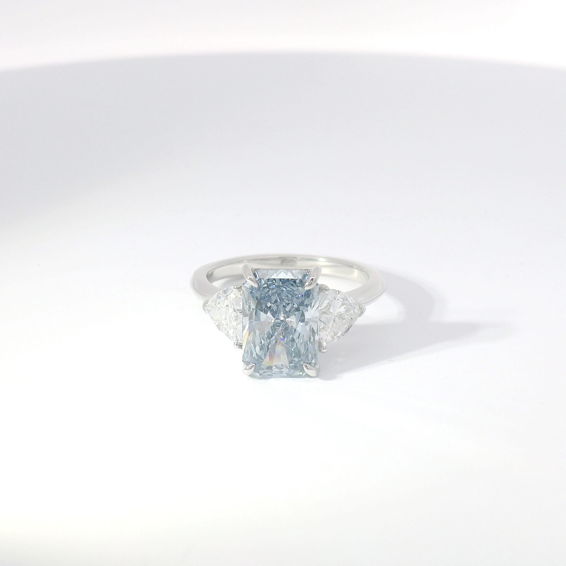 Fancy blue radiant diamond three-stone with trillion-cut side diamonds in platinum