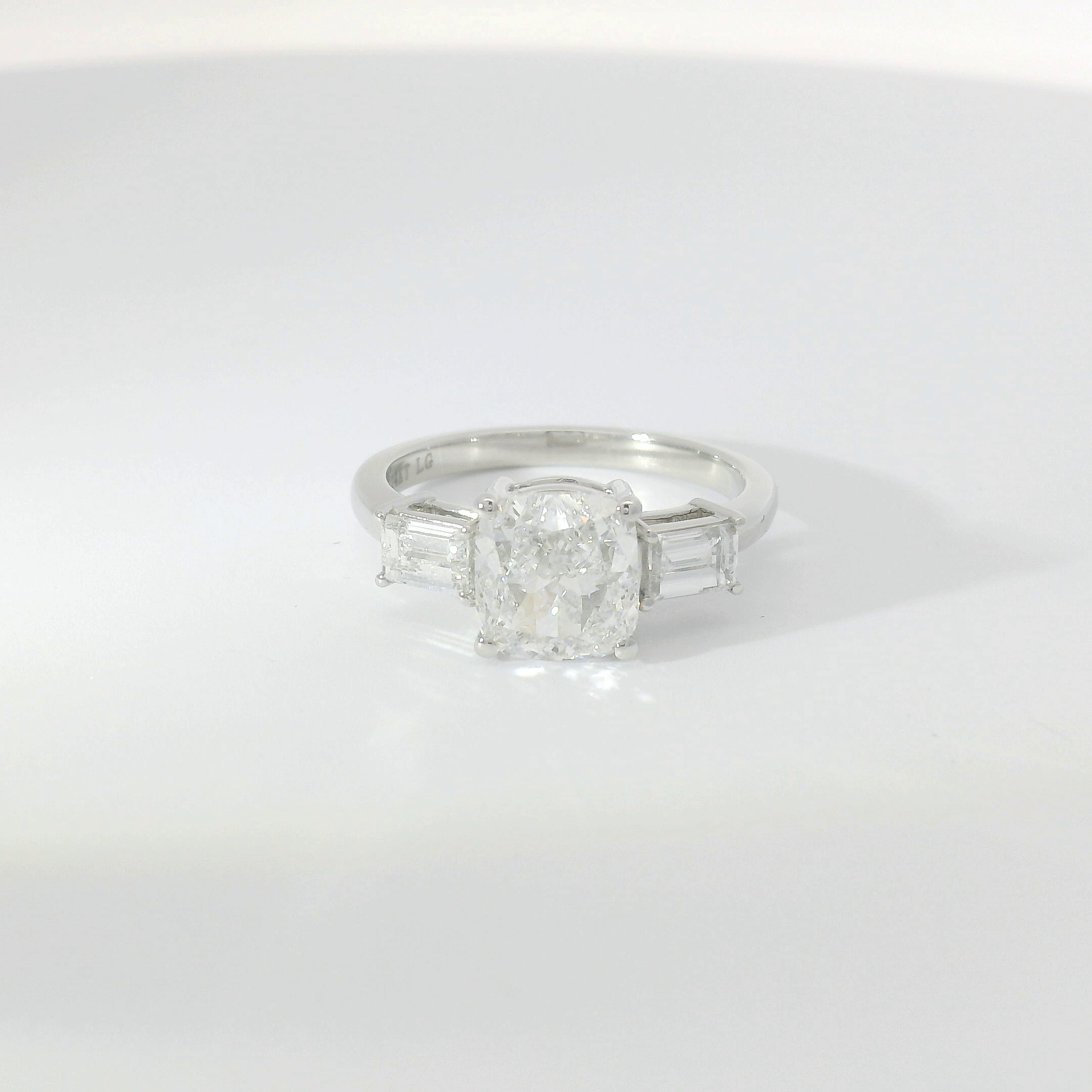Cushion-cut diamond three-stone with step-cut baguette side stones in platinum