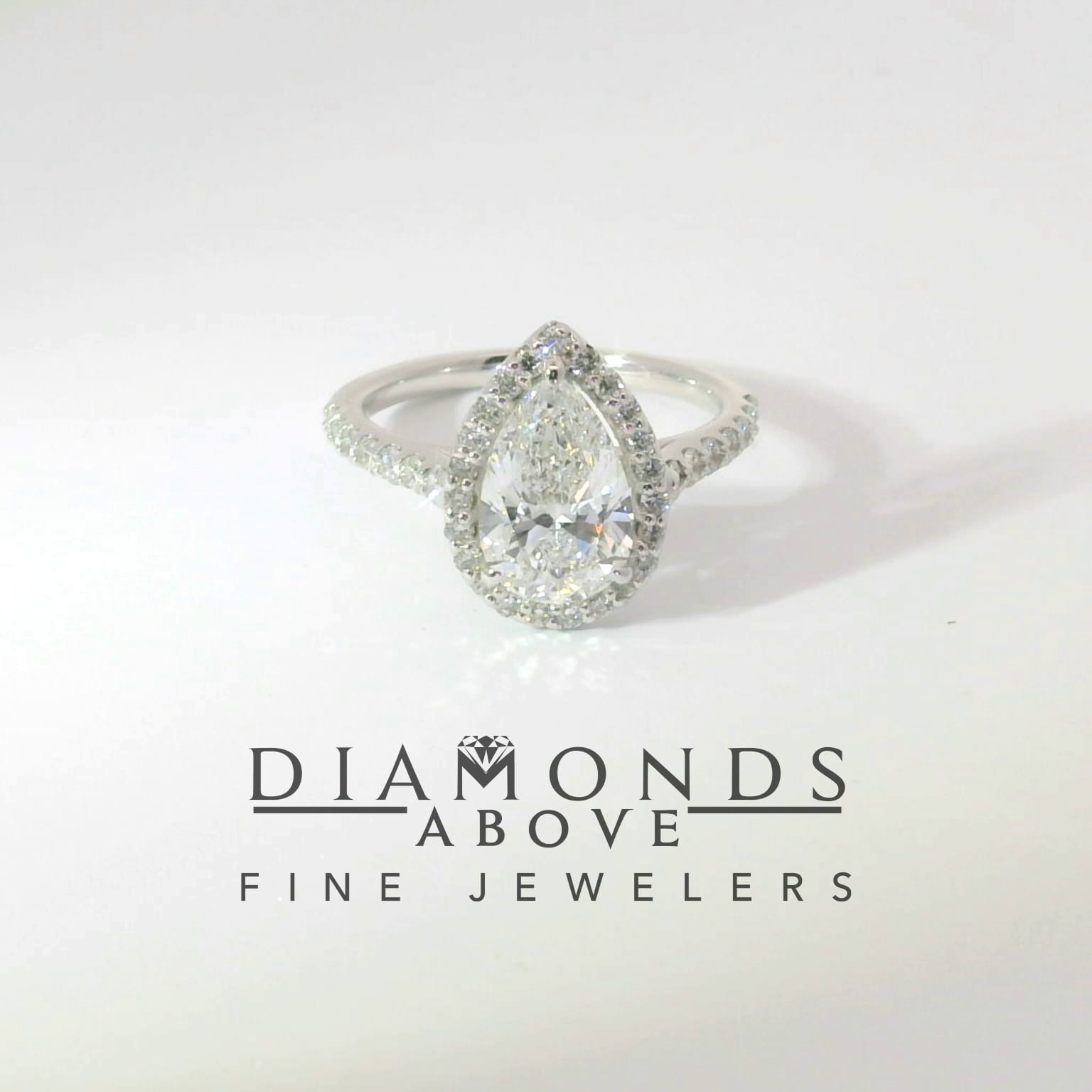 Pear-shape diamond with halo and pavé band in white gold