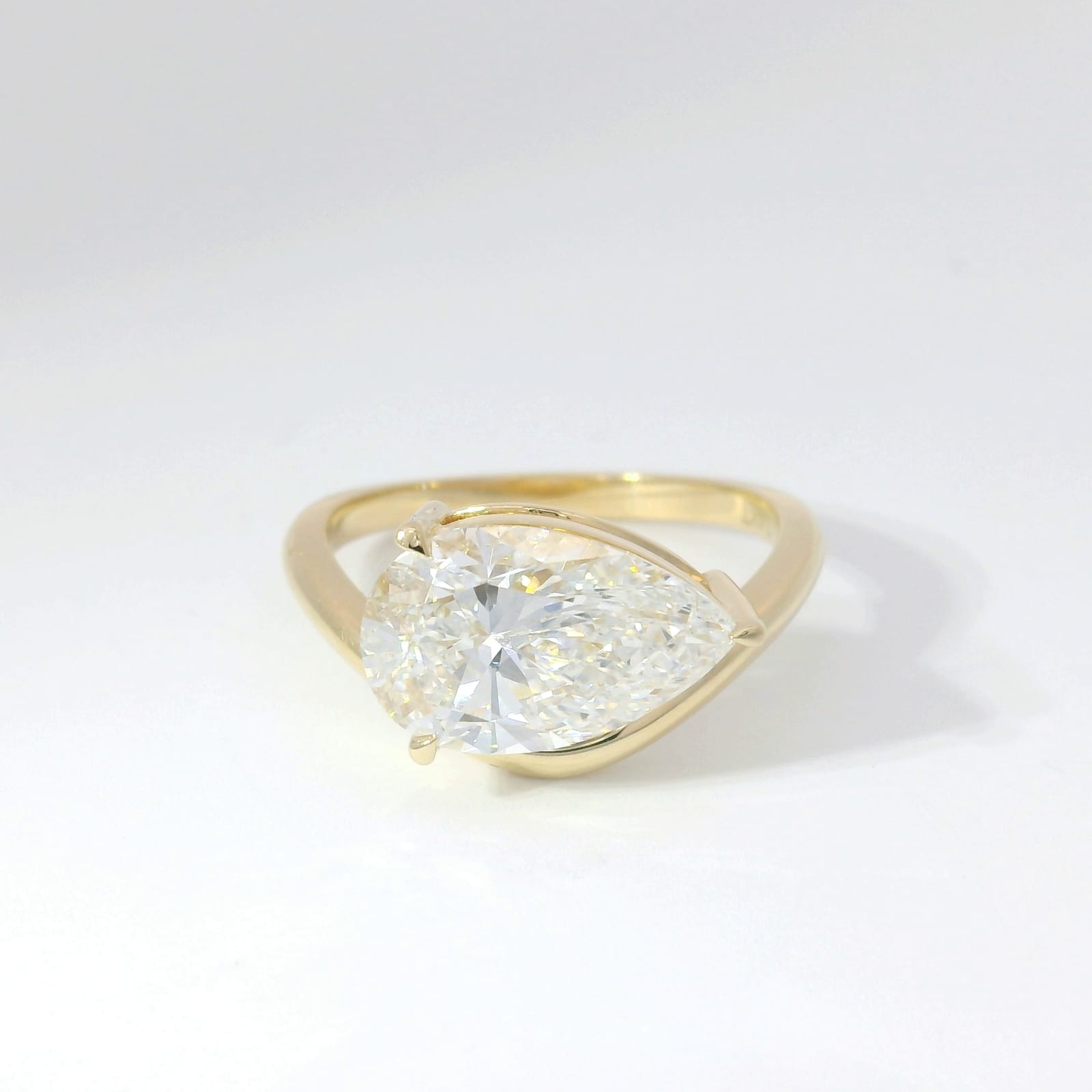 East-west set pear-shape diamond solitaire in yellow gold with curved band