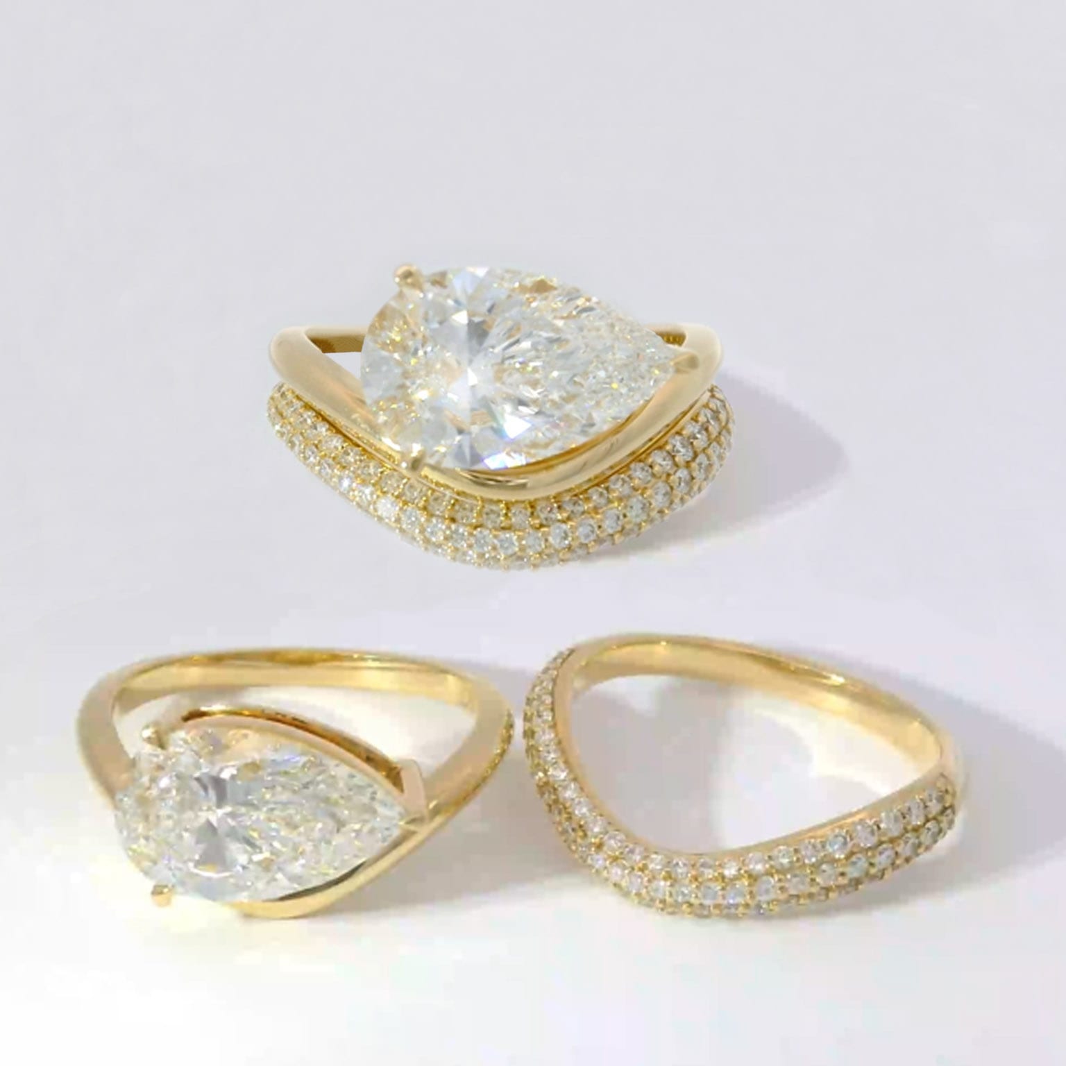 Pear-shape diamond engagement ring shown with curved diamond pavé wedding bands in yellow gold