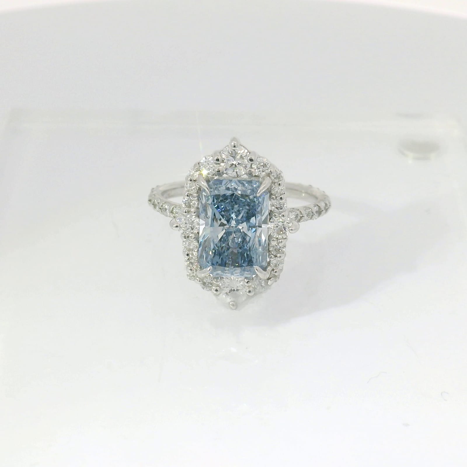 Radiant-cut fancy blue sapphire with diamond halo and pavé shank in white gold