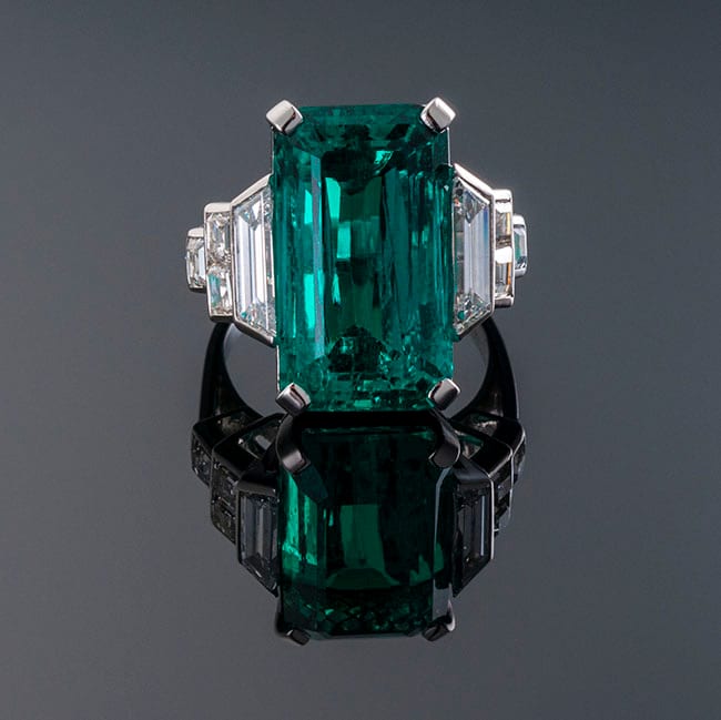 Emerald-cut emerald three-stone ring with trapezoid diamond sides in platinum