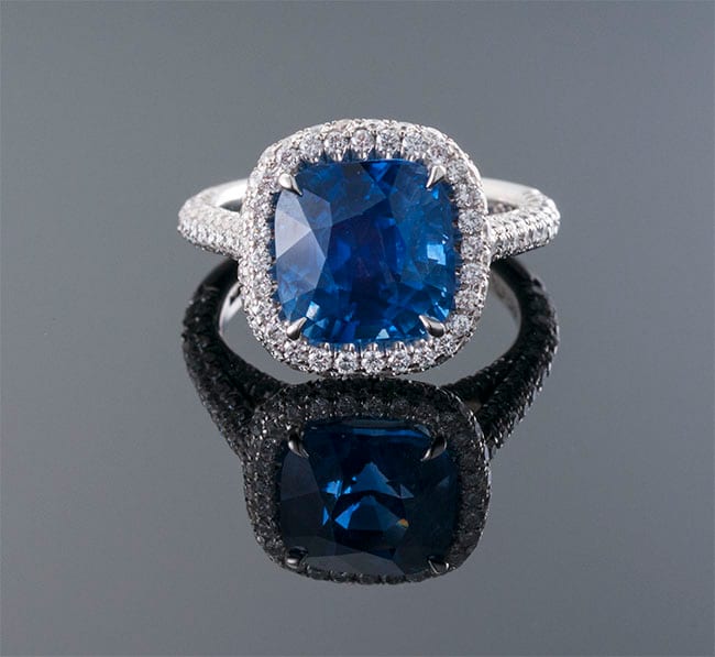 Cushion-cut blue sapphire halo ring with diamond pavé split shank