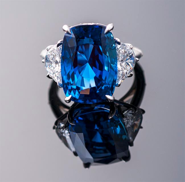 Cushion-cut blue sapphire three-stone ring with half-moon diamond side stones