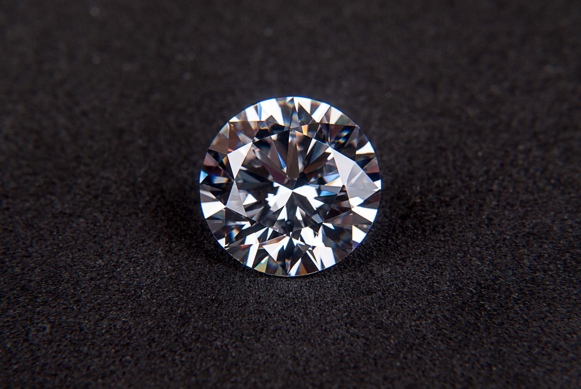 Round brilliant diamond showcased on black velvet, indistinguishable from natural